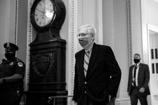  Mitch McConnell, wearing a mask, walking in the Capitol.