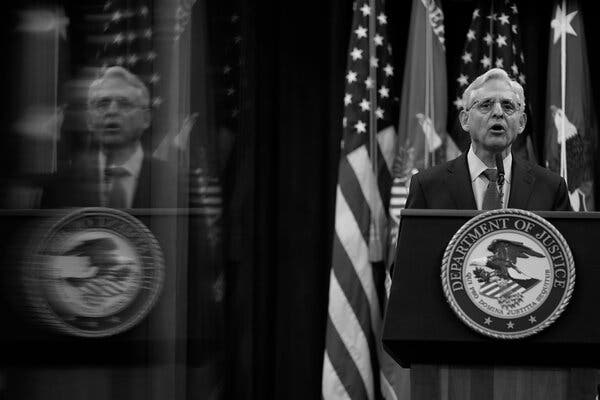 Attorney General Merrick Garland speaking behind a lectern with the seal of the Department of Justice, with flags in the background.
